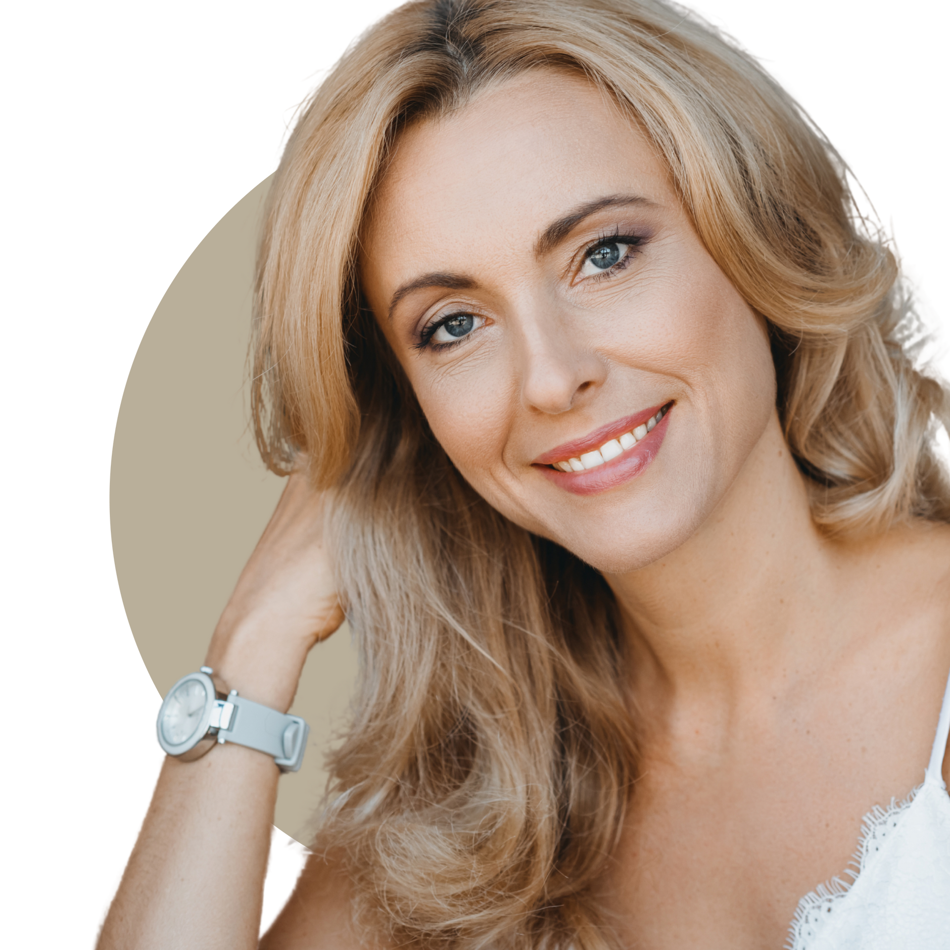 A woman with long curly hair is smiling and touching her face.