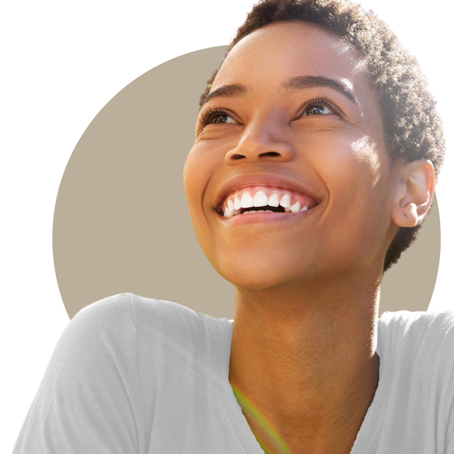 A woman with long curly hair is smiling and touching her face.