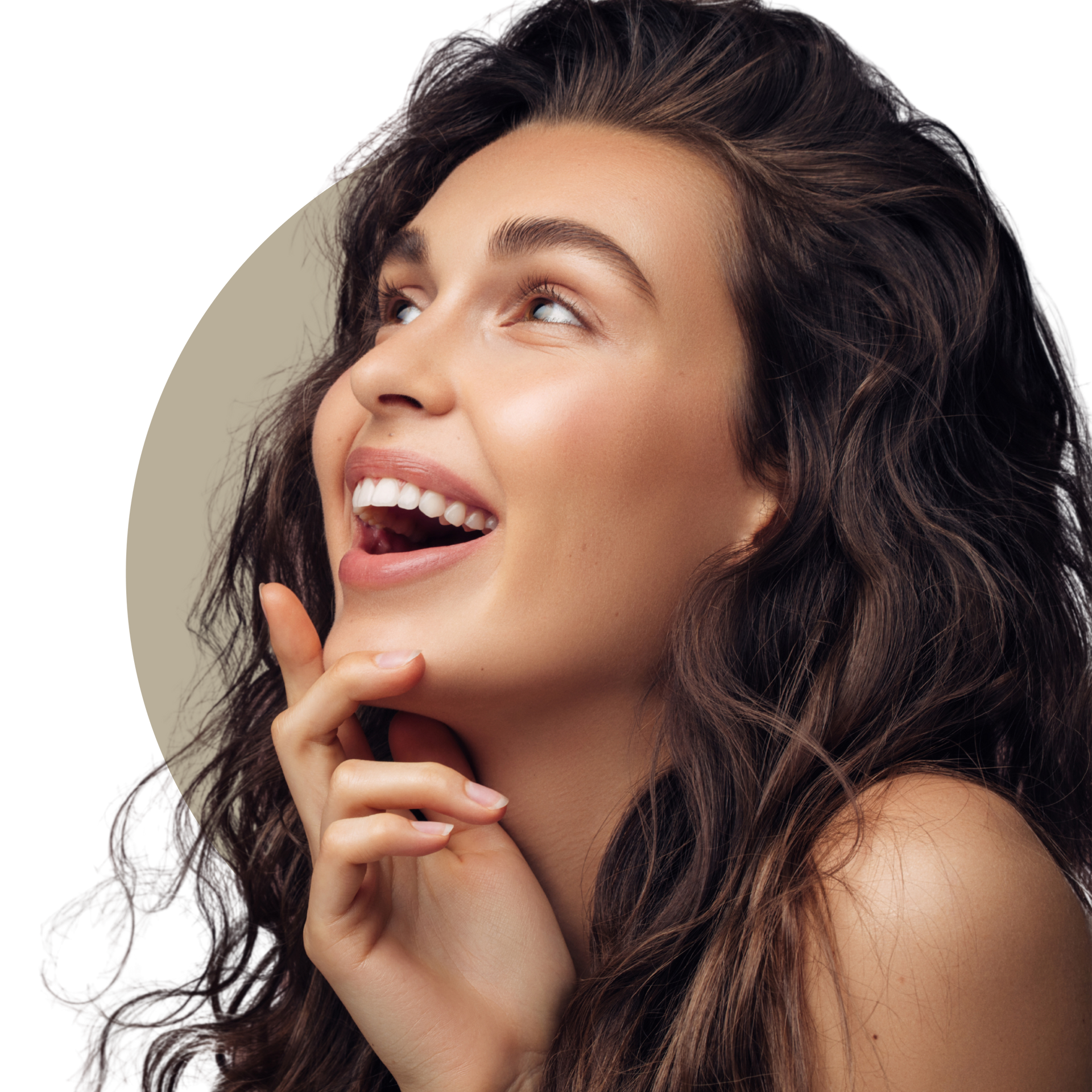 A woman with long curly hair is smiling and touching her face.