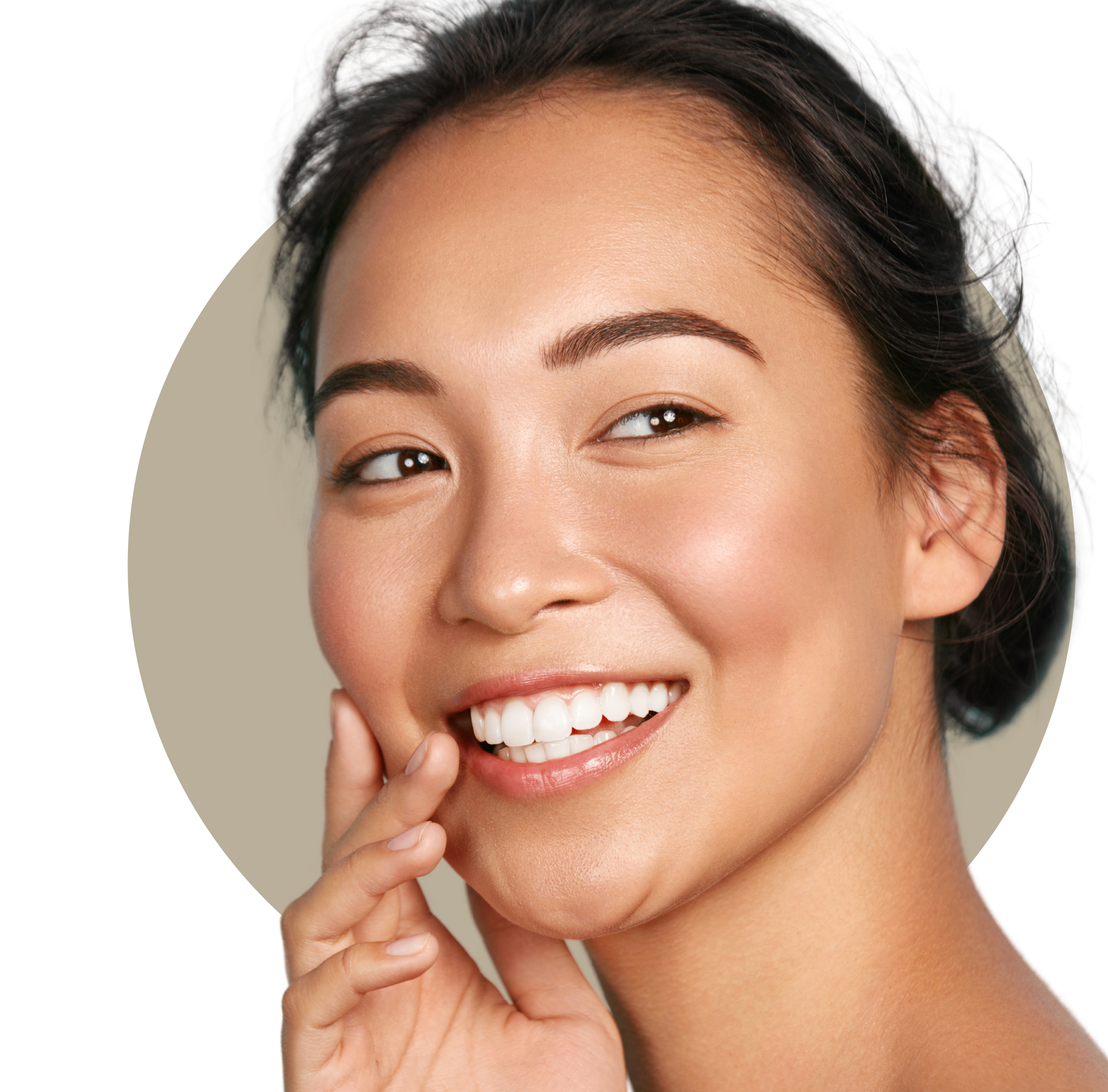 A woman with long curly hair is smiling and touching her face.