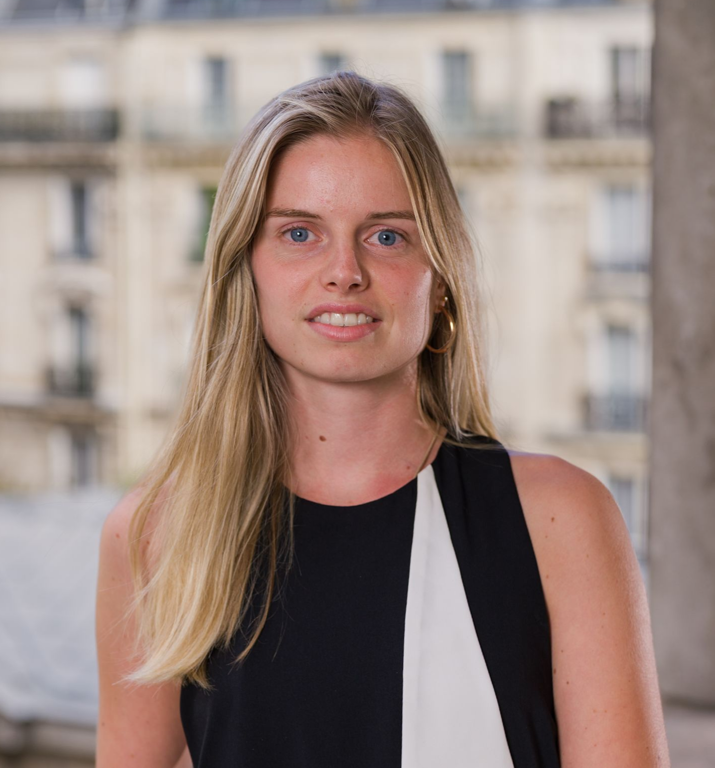 Une femme portant des lunettes et une chemise noire sourit à la caméra.