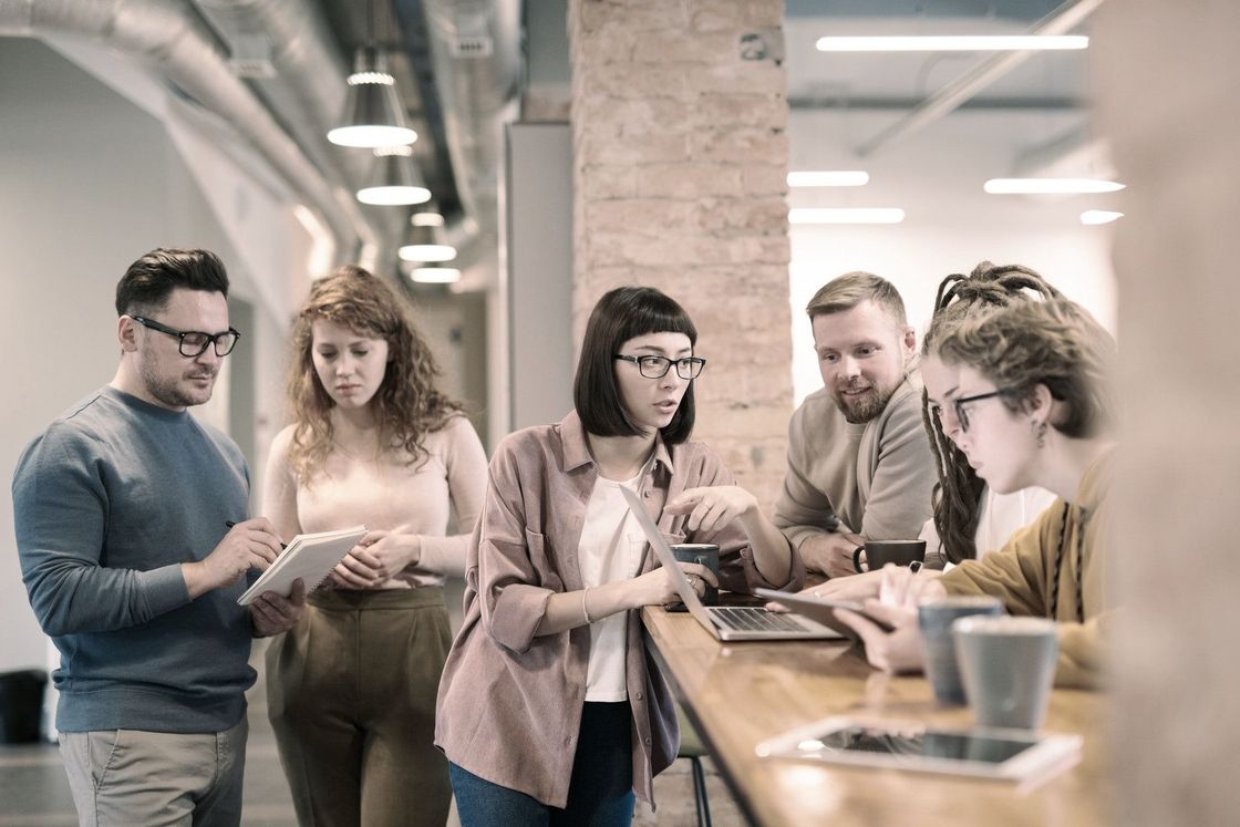 Un groupe de personnes se tient autour d'une table et regarde une tablette.