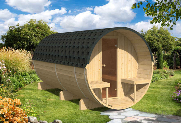 A wooden barrel with a black roof is sitting on top of a lush green field.