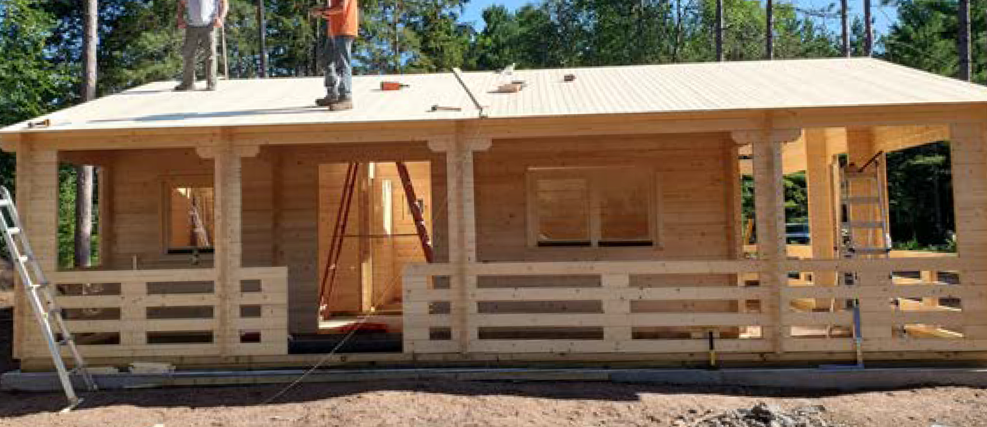 Two men are working on the roof of a wooden house.