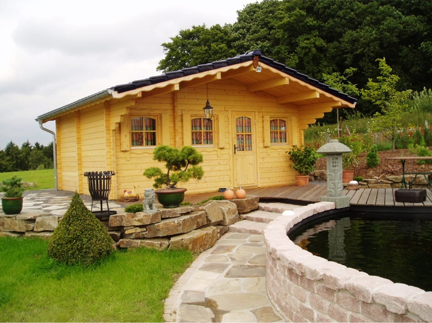 A wooden house with a pond in front of it