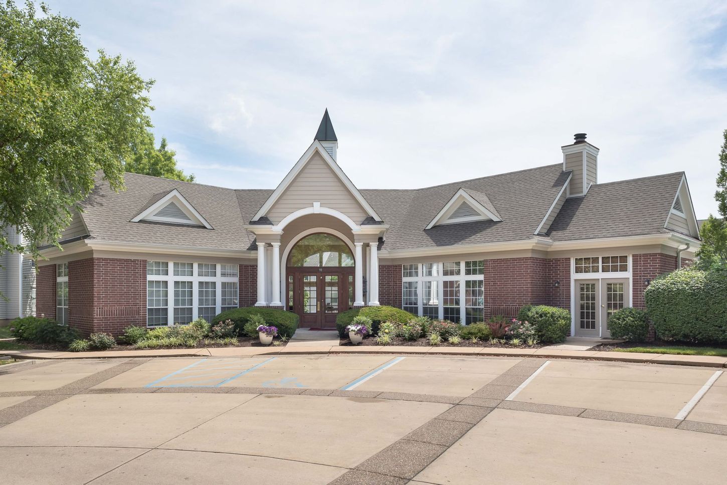 Red brick building with multiple windows and a central arched entrance.  Parking spaces are in front.