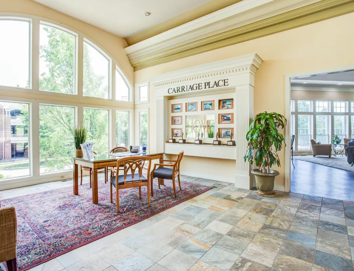 Interior lobby with large windows, a table and chairs, and a display labeled 