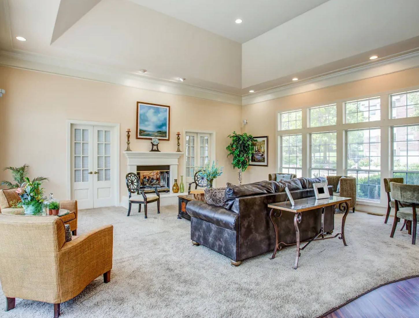 Spacious living room with a large sofa, armchair, fireplace, and tall windows. Neutral color scheme with plenty of natural light.