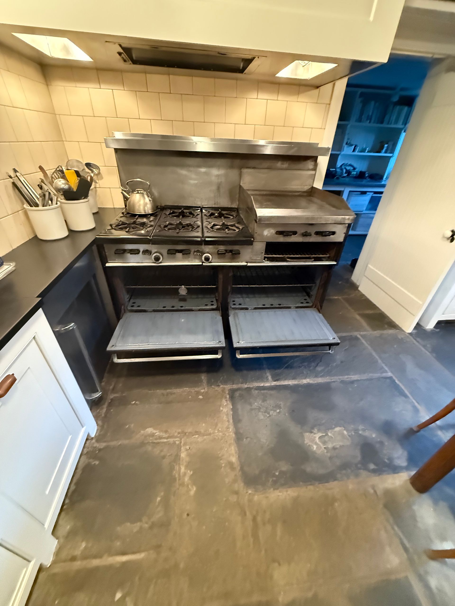 A kitchen with a stove and oven with the doors open.