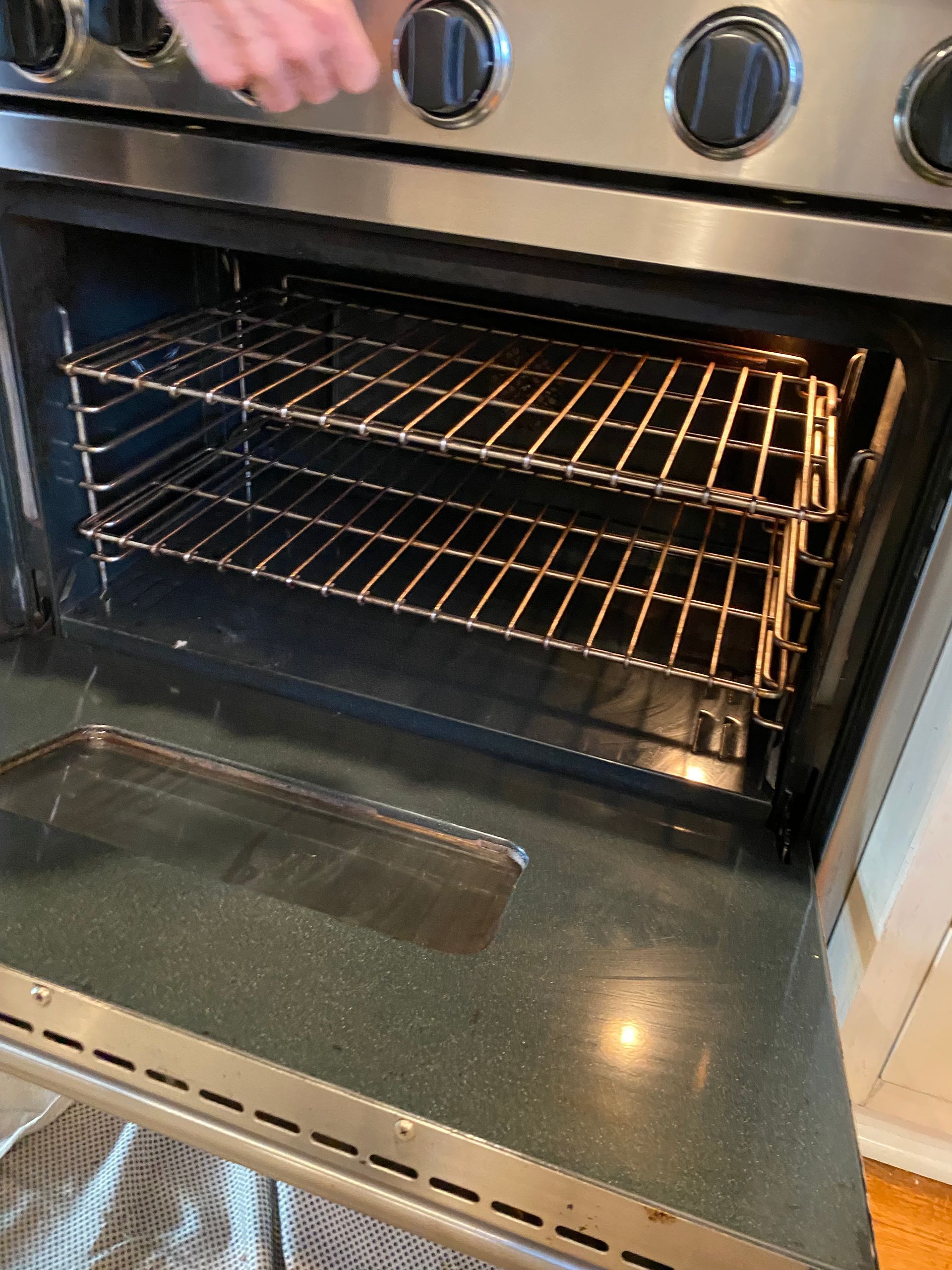 A person is opening the door of a stainless steel oven.