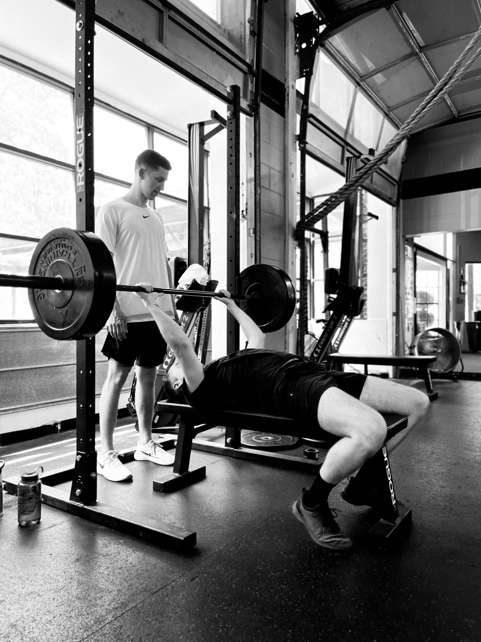 A black and white photo of a man lifting weights in a gym