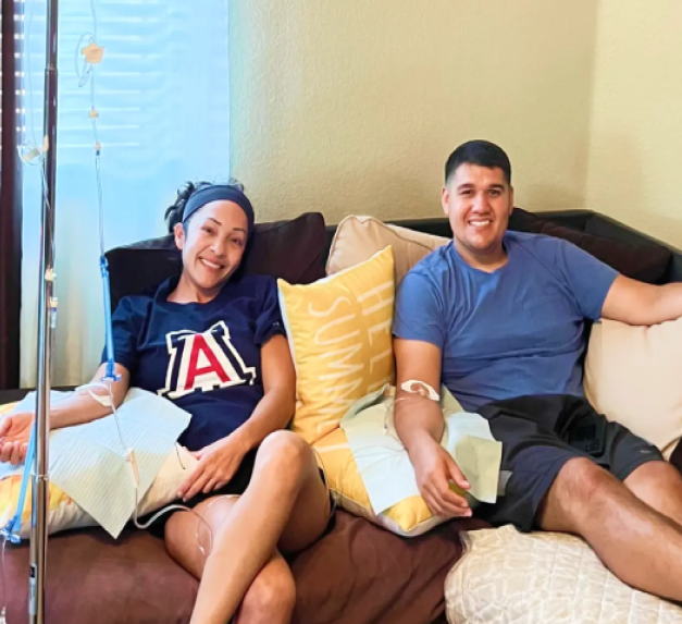 A man and a woman are sitting on a couch with an iv in their arm