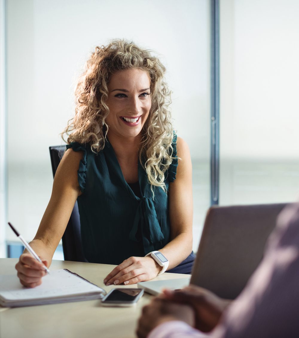 Smiling woman taking notes while having a productive meeting with a client.
