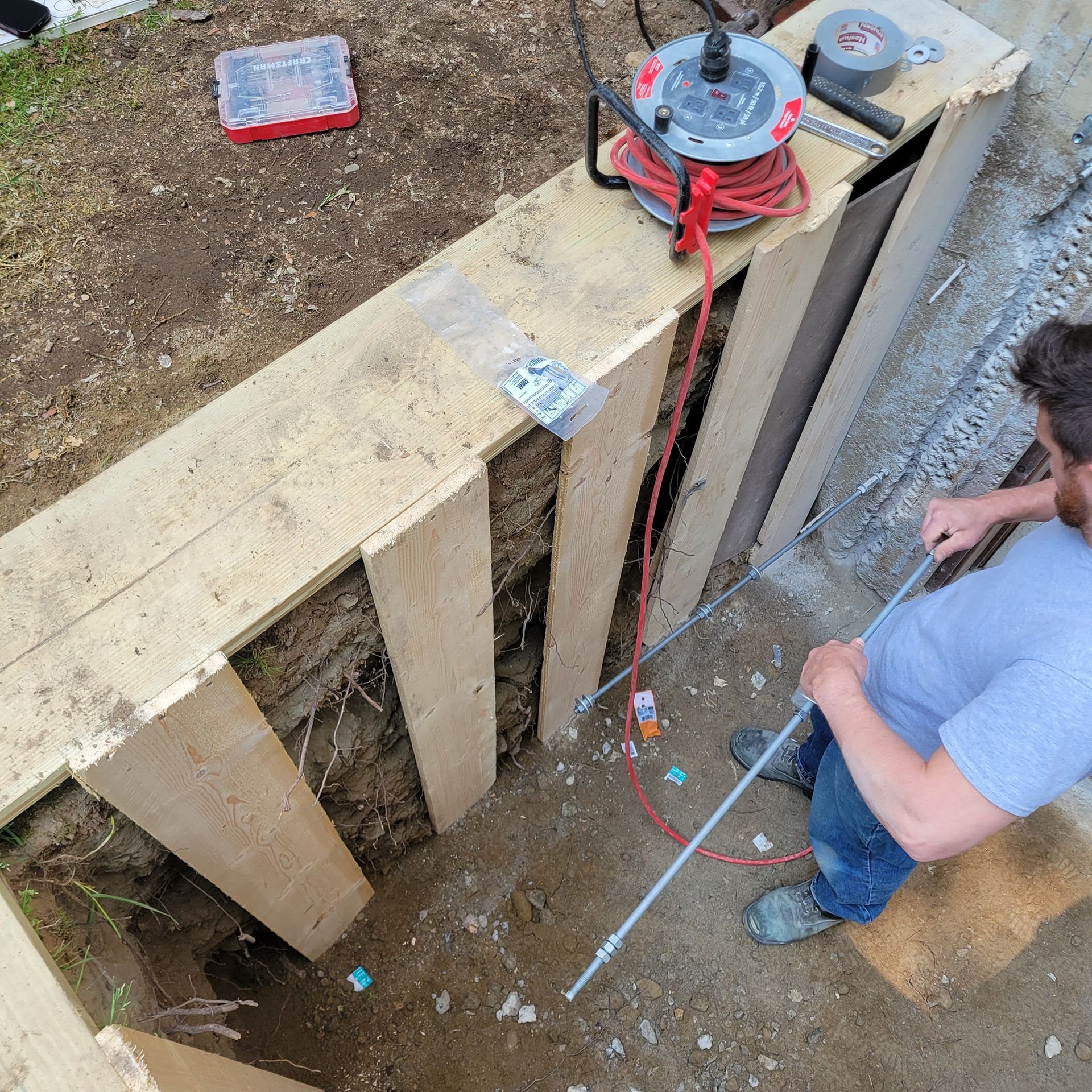 A man is digging a hole in the ground with a tape measure