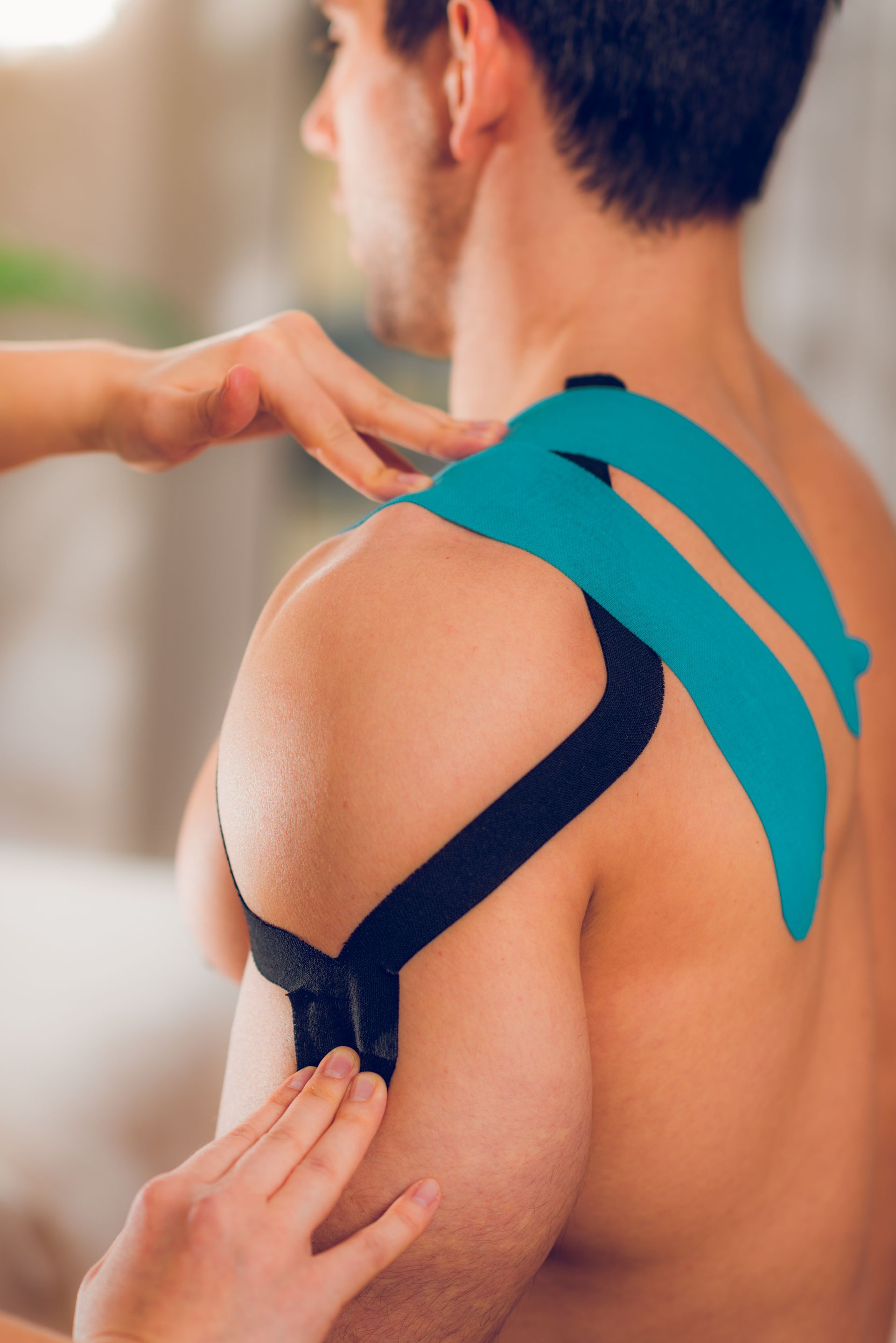 a man is getting kinesio tape on his shoulder .
