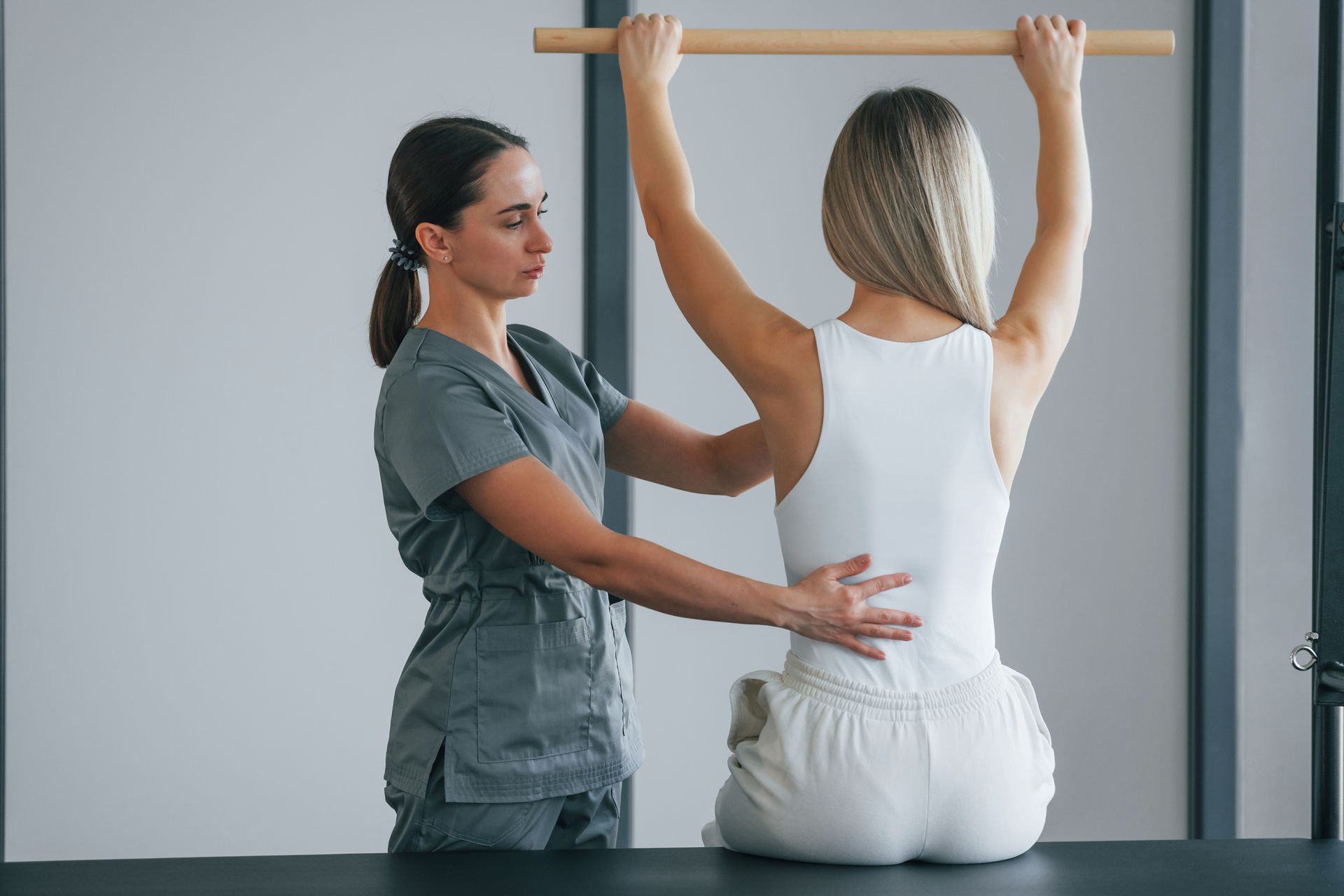 a woman is sitting on a table while a nurse helps her with exercises .