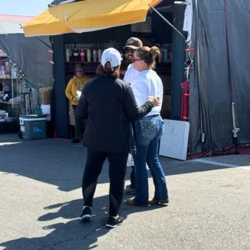 People conversing near a food stand.