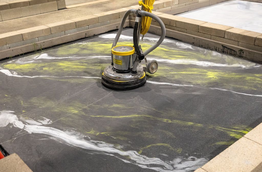 Epoxy resin flooring in the middle of installation with an industrial-rated concrete floor grinder and polishering on top of it.