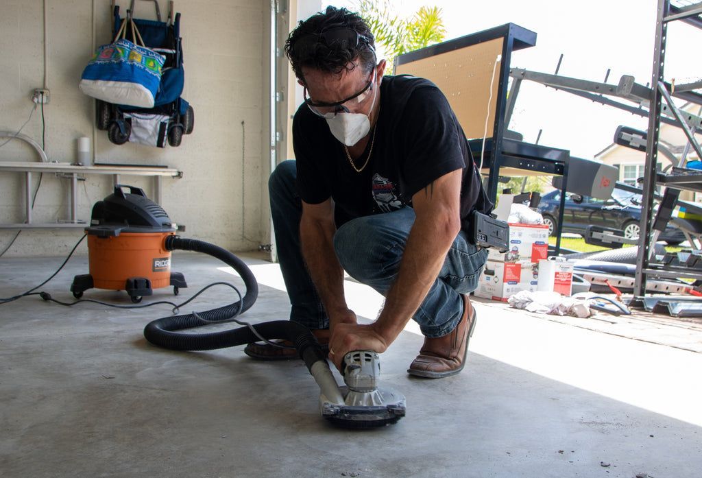 A contractor using a hand angle grinder with diamond concrete grinding tooling to prepare a concrete surface for epoxy resin installation.