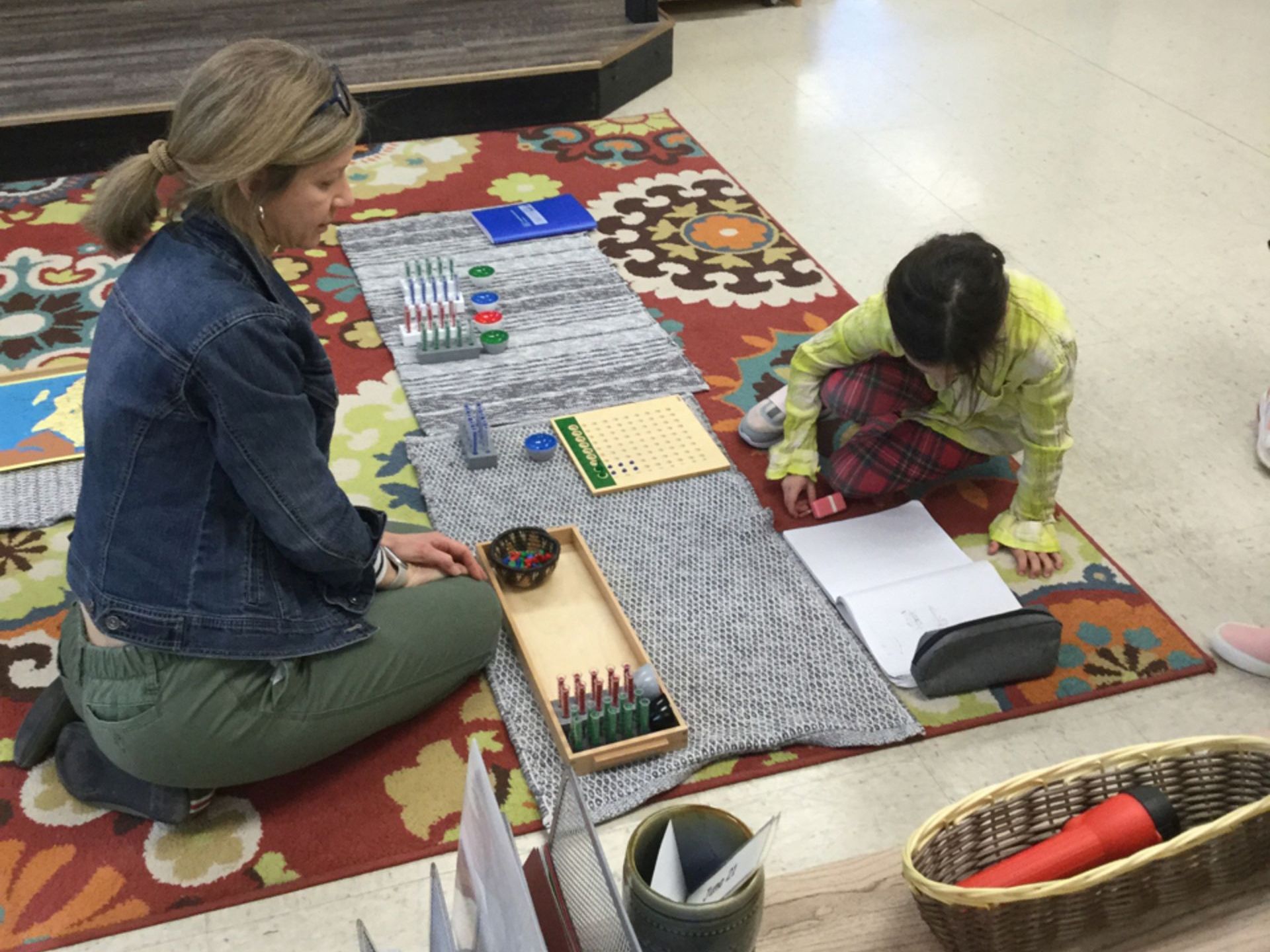 Montessori guide and child working with math materials