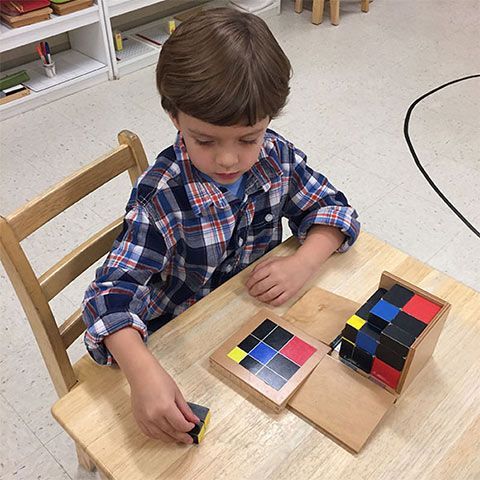 Montessori child working with the trinomial cube math material