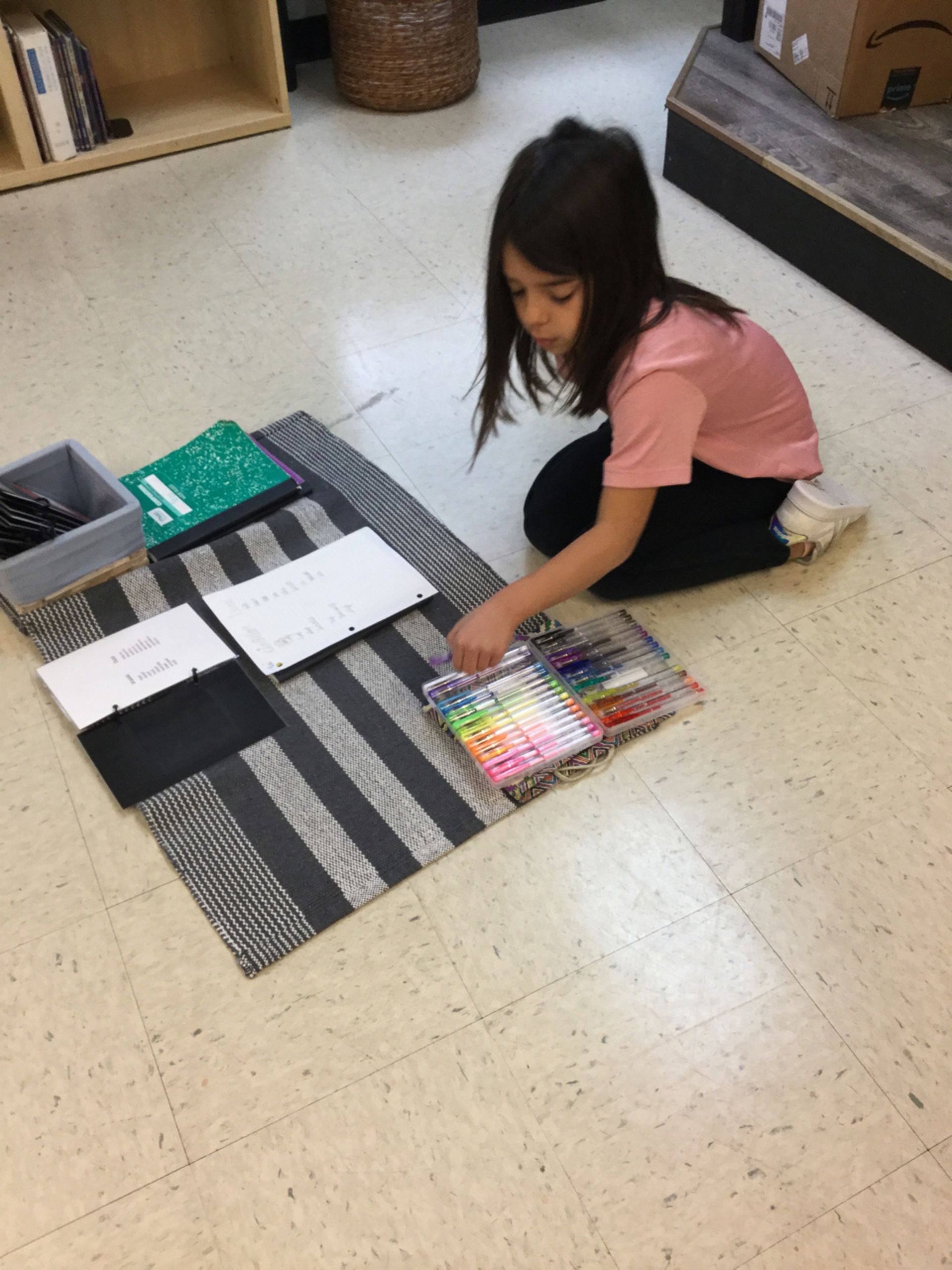 a Montessori child is sitting on the floor playing with crayons