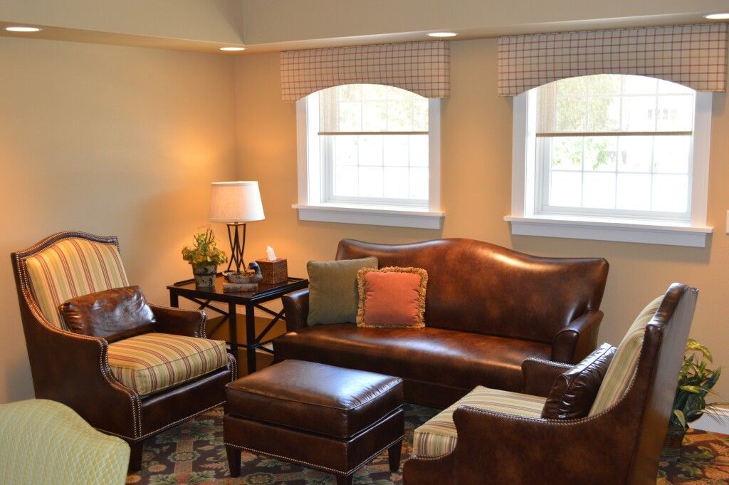 A living room with a couch , chairs , and ottoman.
