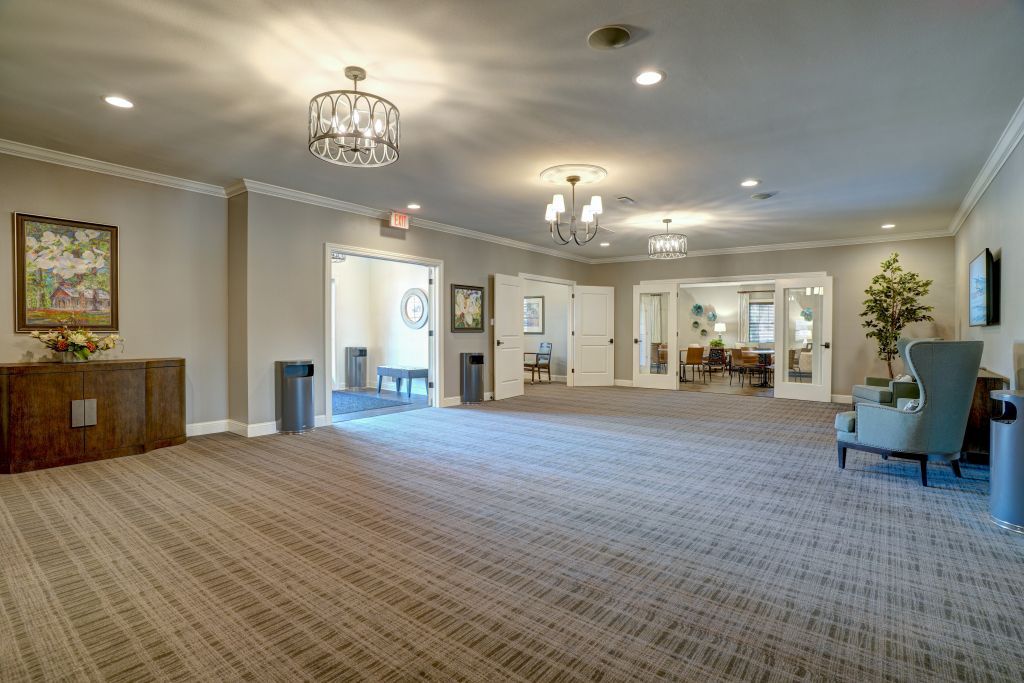 A large empty room with a carpeted floor and a chandelier.