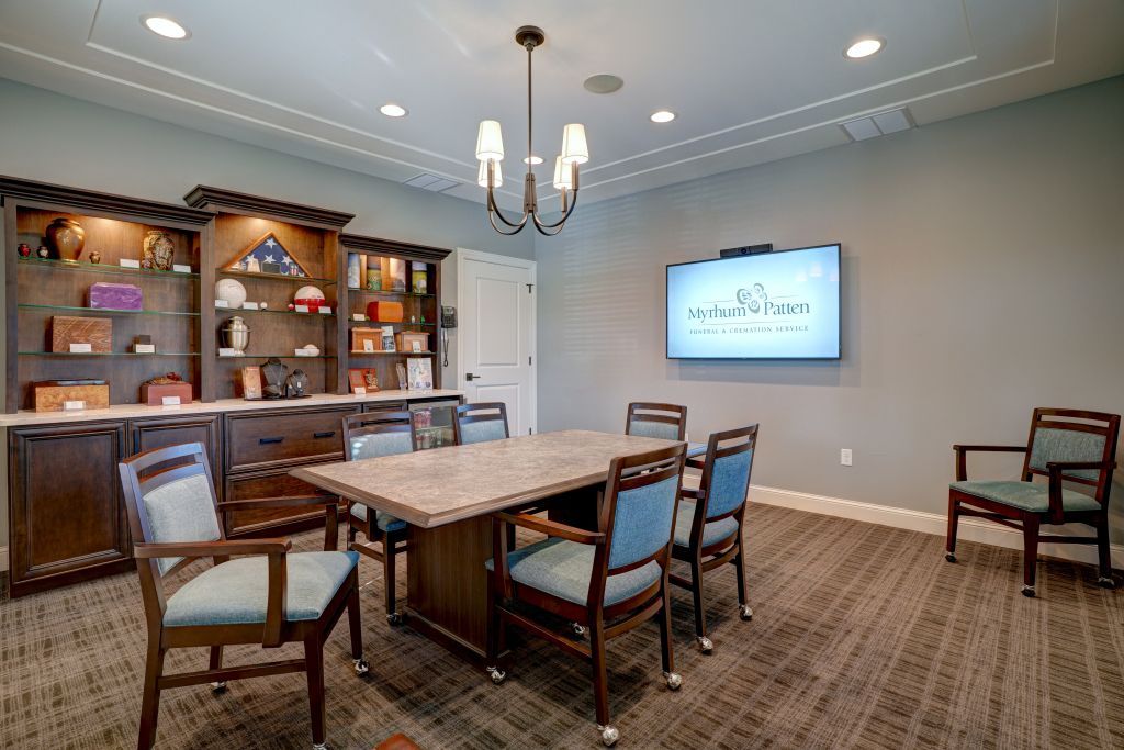 A conference room with a large table and chairs and a flat screen tv.