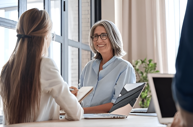 A young woman is talking to an older woman in a wheelchair.