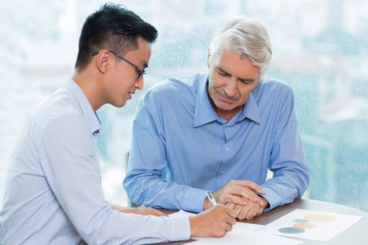 A man is sitting on a couch talking to two older people.