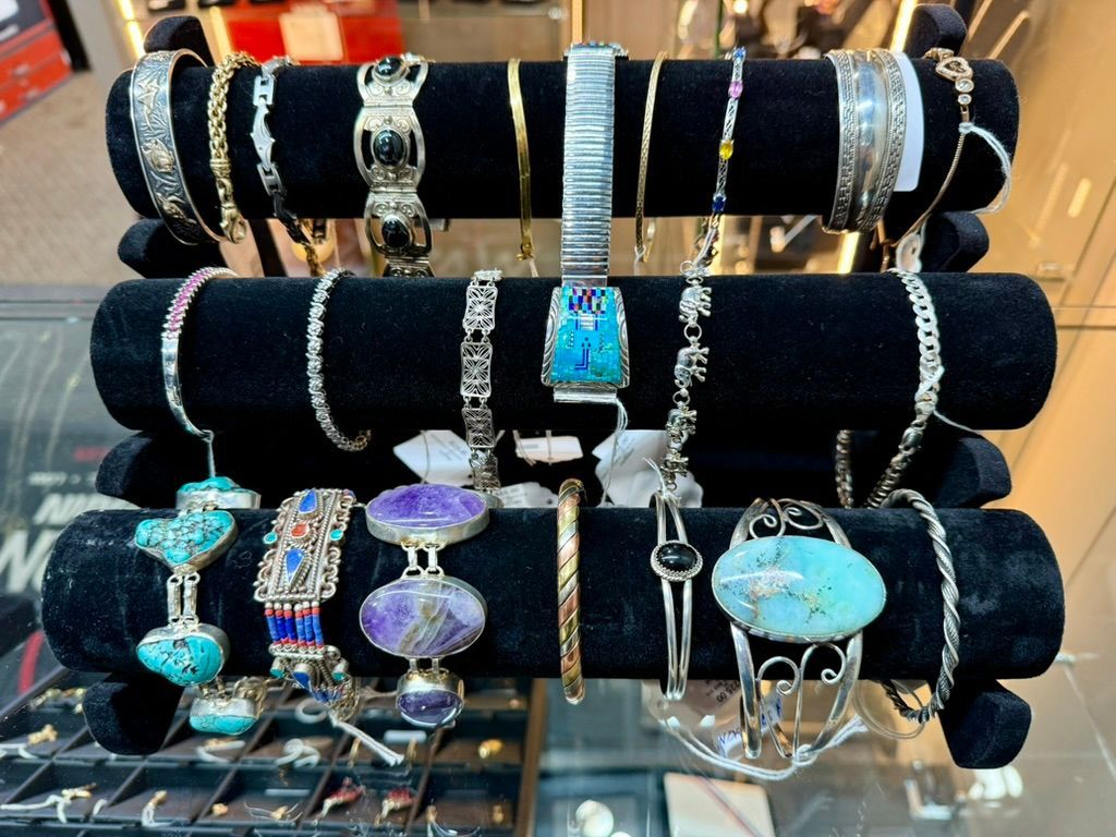A black velvet jewelry display stand holds various bracelets, including turquoise, silver, and gemstone designs.
