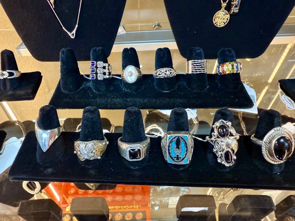 A display stand in a jewelry store showcasing an assortment of silver and gemstone rings arranged in two rows.