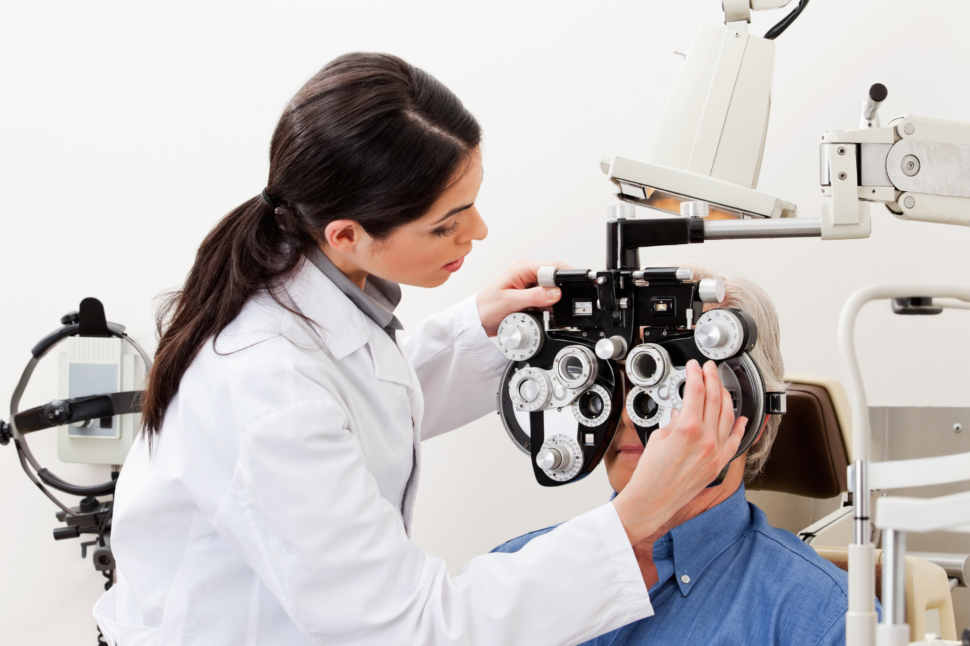 A woman in a purple shirt and glasses is smiling while sitting in front of a lamp.