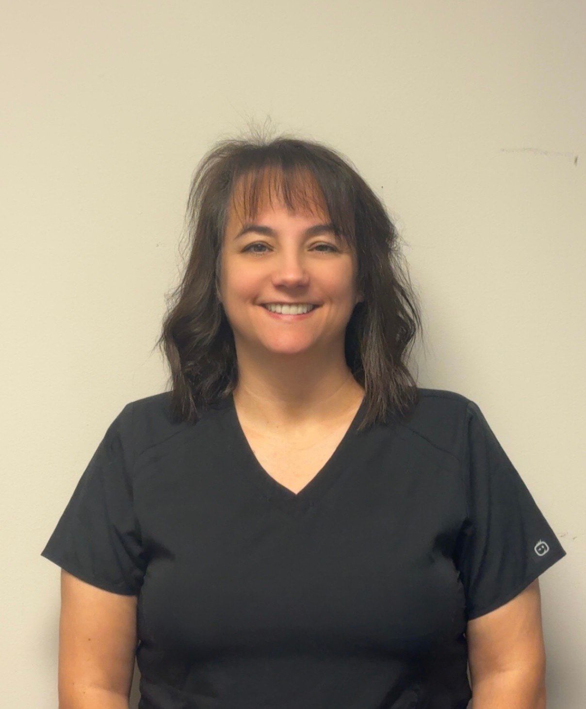 Woman with dark hair smiling at the camera, black background.