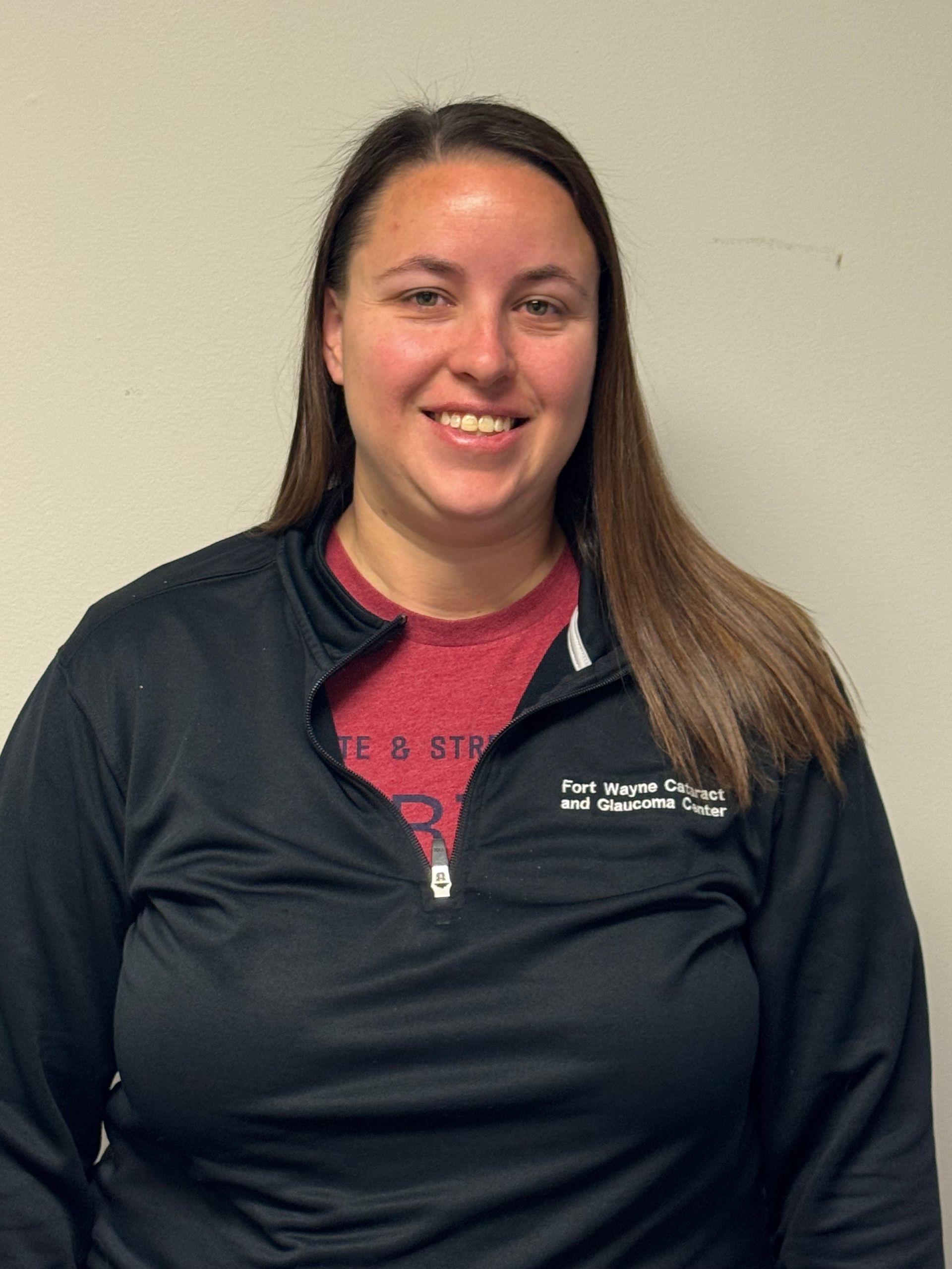 Woman with reddish-brown hair smiling at the camera, wearing a purple tank top.
