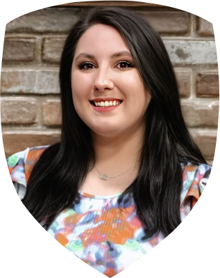 A woman is smiling in front of a brick wall