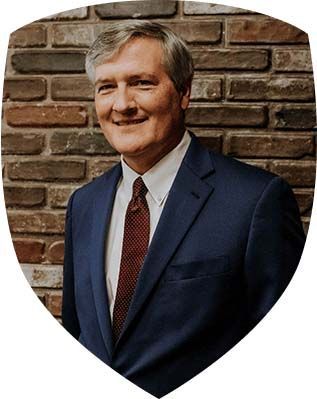 A man in a suit and tie is standing in front of a brick wall.