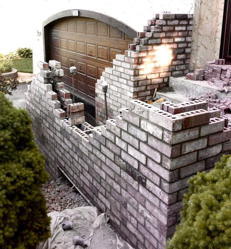 A brick wall is being built in front of a garage door