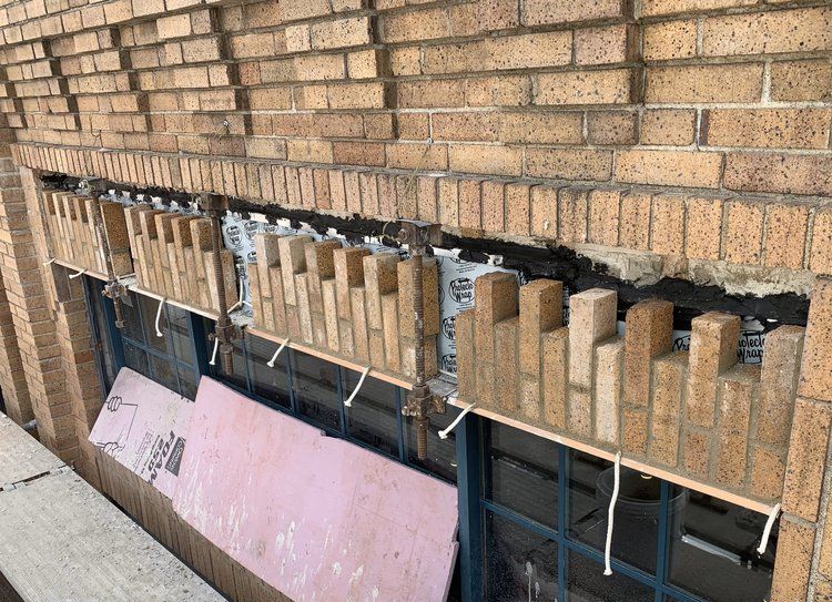 A brick wall with a window and bricks hanging from it.