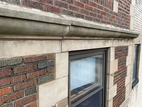 A brick building with a window and gutter on the side.