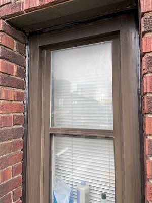 A window with blinds on a brick building.