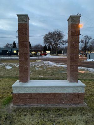 Two brick pillars are sitting next to each other in a grassy field.
