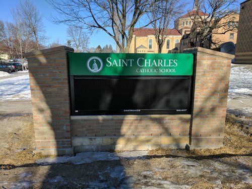 A sign for saint charles school is sitting on a brick wall.