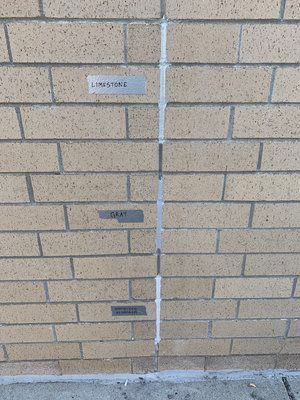 A brick wall with a hole in it and a piece of tape on it.