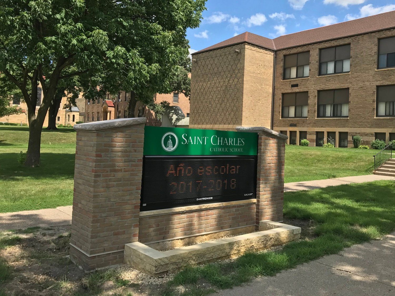 A large brick building with a green sign in front of it