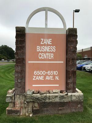 A sign for the zane business center is sitting on top of a brick building.