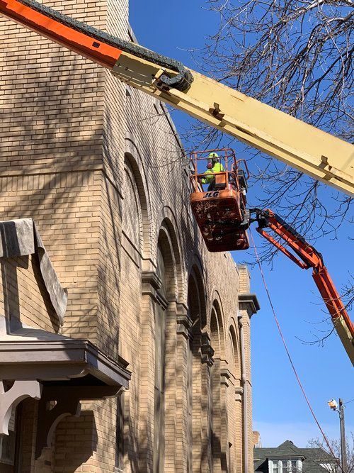 A man is working on a brick building with a crane.