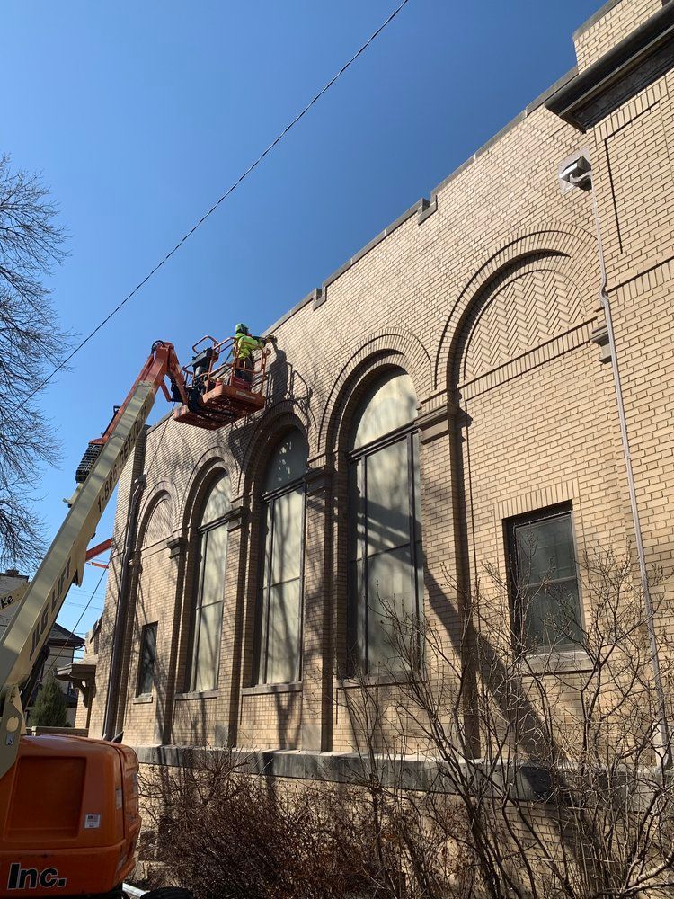 A crane is being used to clean a brick building.