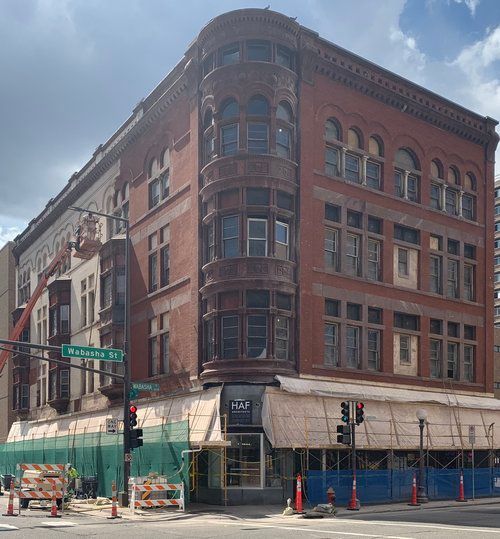 A large brick building is on the corner of a city street.